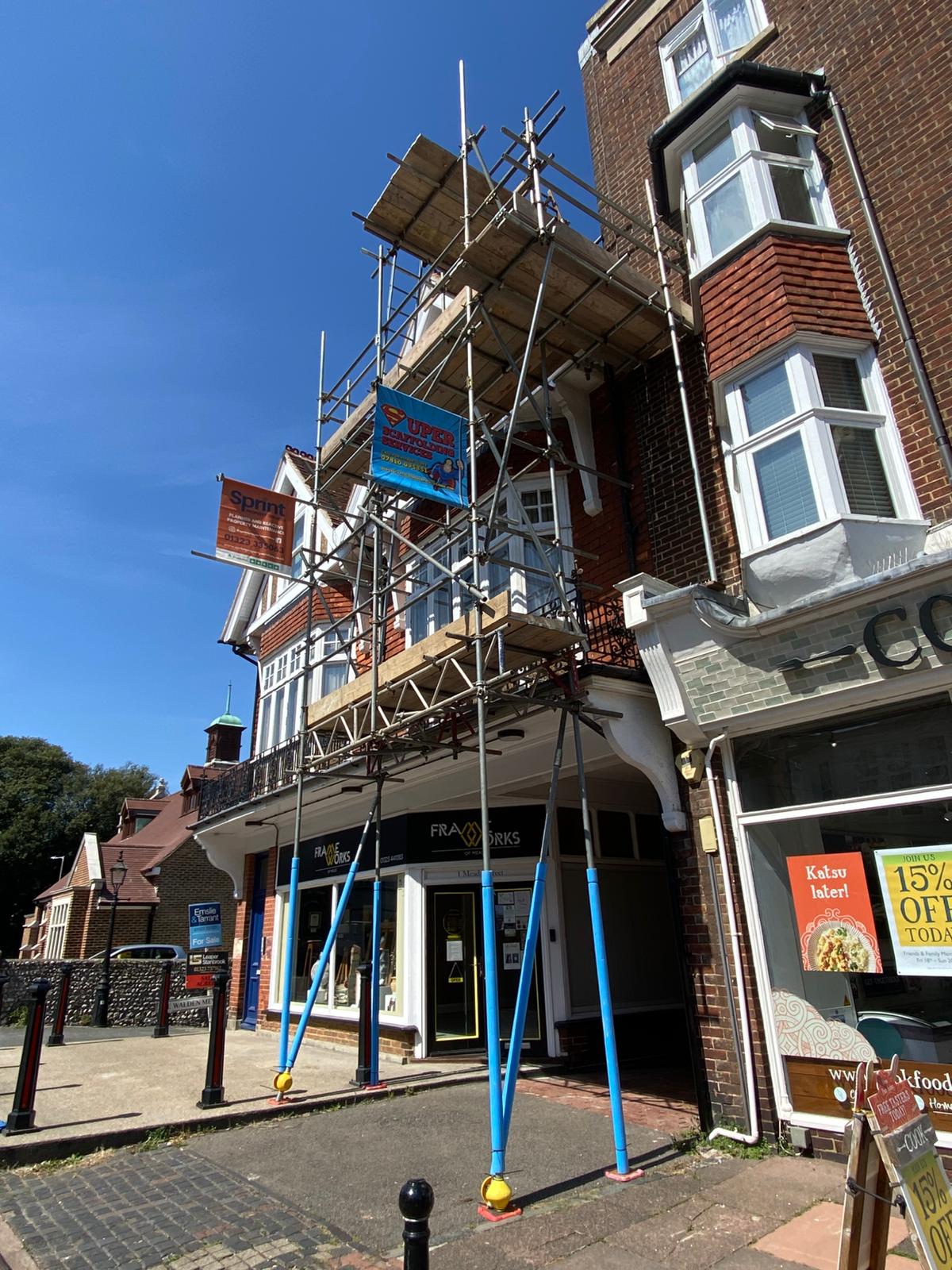 Three-storey corner shopfront parade fully scaffolded with the Super Scaffolding banner
