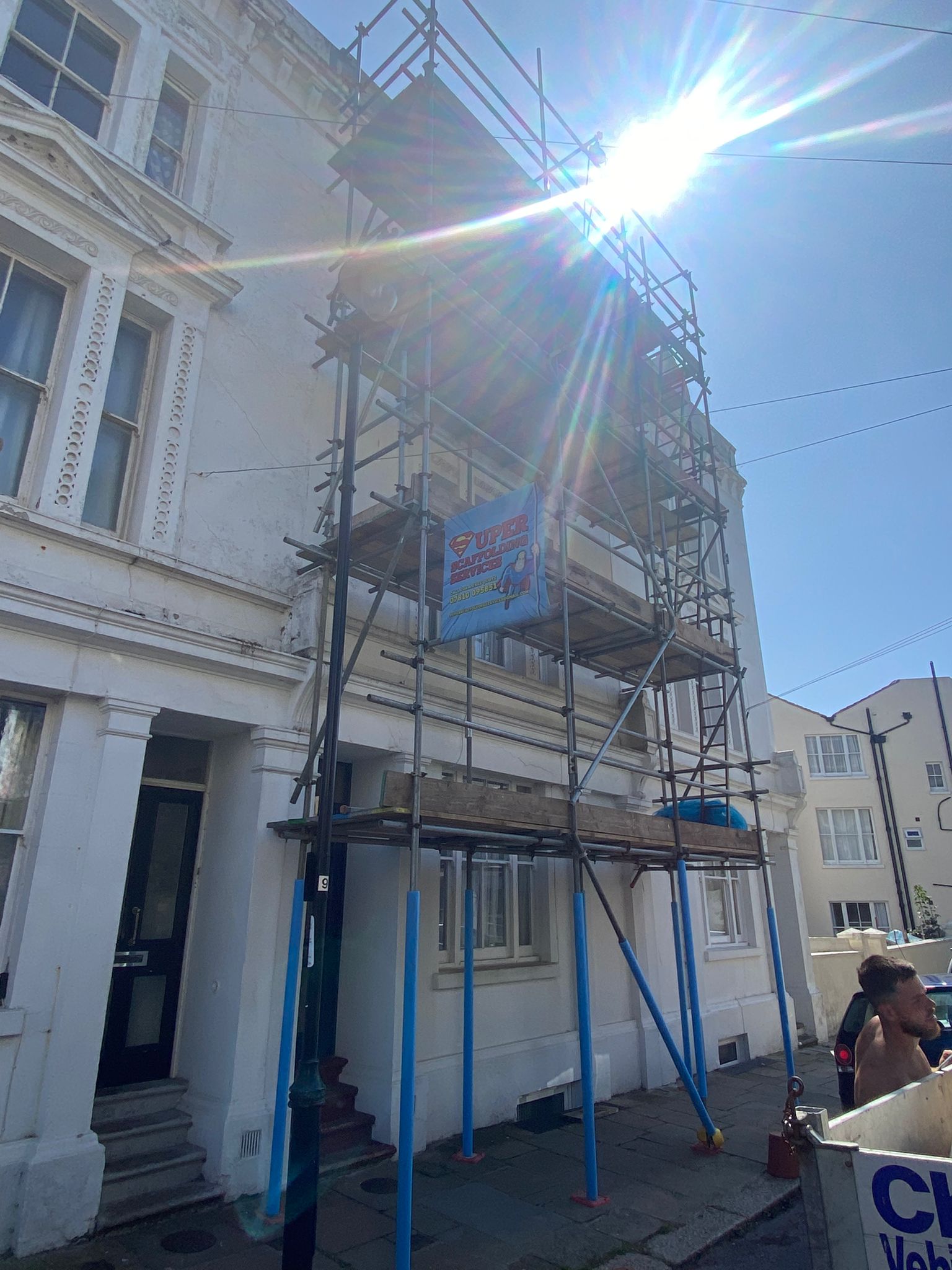 Full-height scaffold on a white rendered Victorian townhouse in bright sunshine