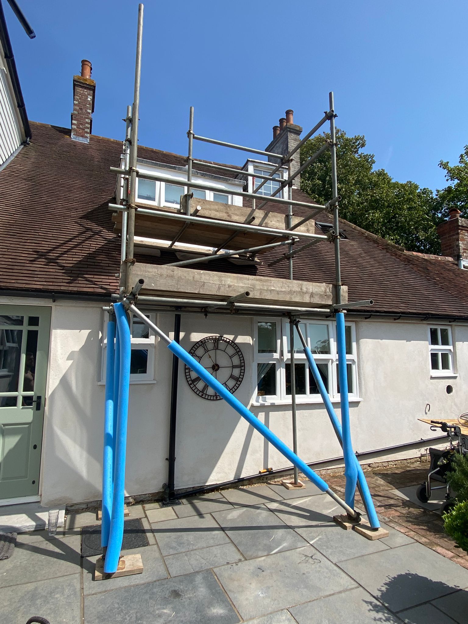 Scaffold with blue raking props built against a white cottage